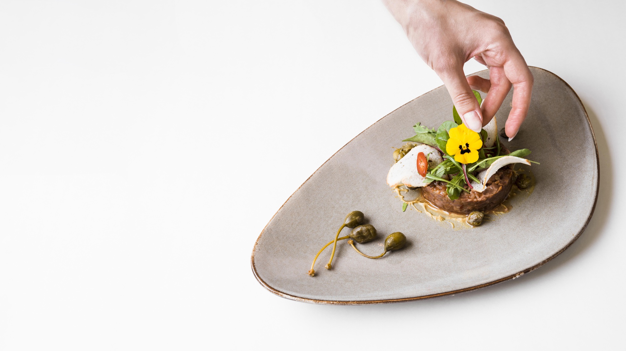 Chef arranging plated seasonal dish on wooden table